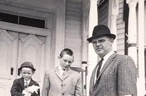 Charles and sons A father and two sons stand on their front porch dressed in suits.