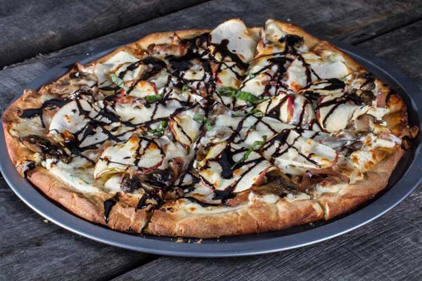 White pizza with apple slices, drizzled with balsamic dressing.