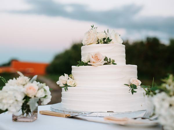 A three their wedding cake with peach roses on alternating tiers.