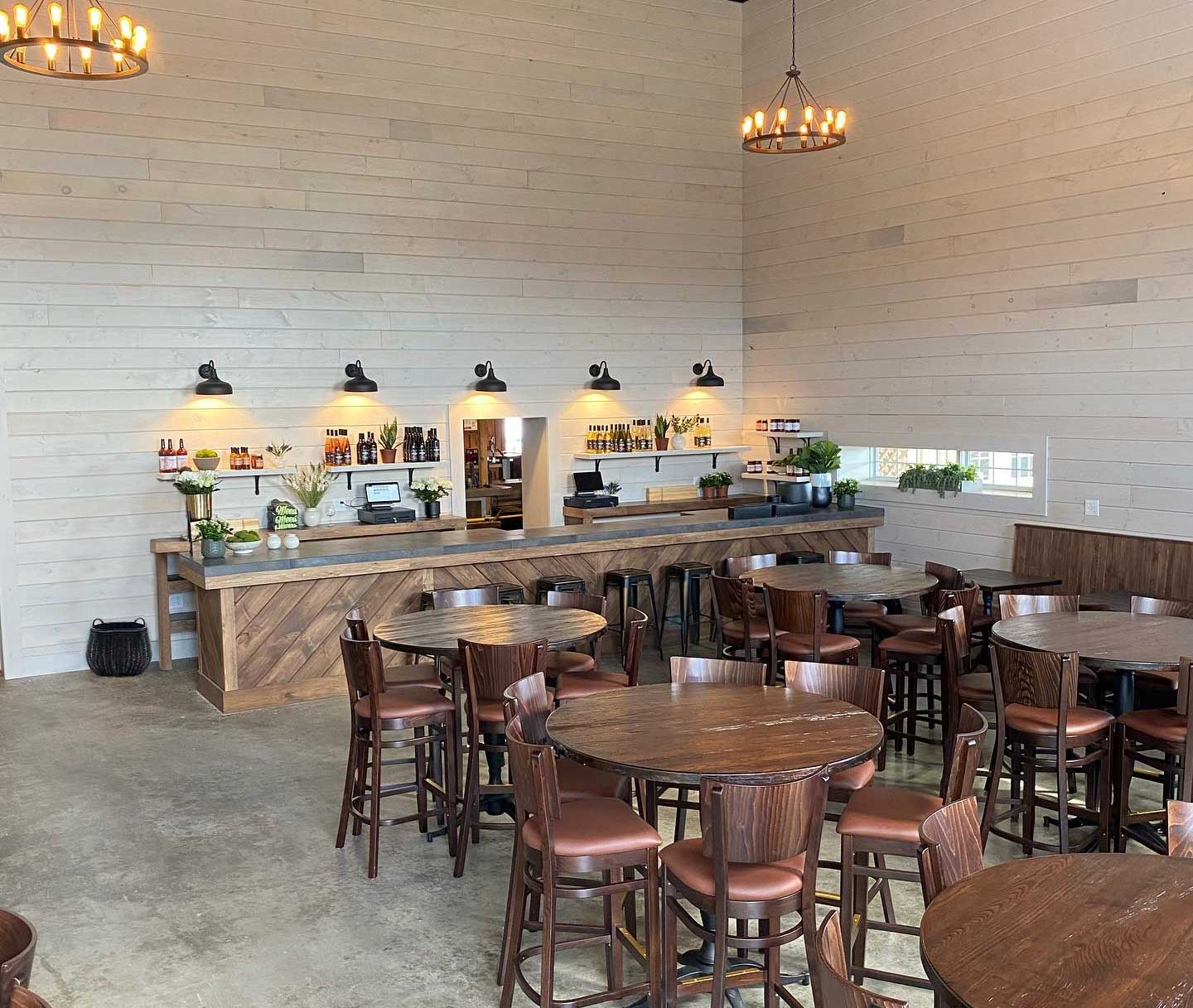A bright white open room with wood table seating and rustic lighting fixtures