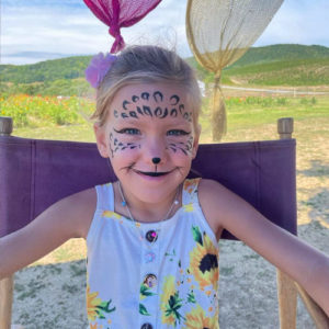 A young girl poses with face paint to look like a cheetah