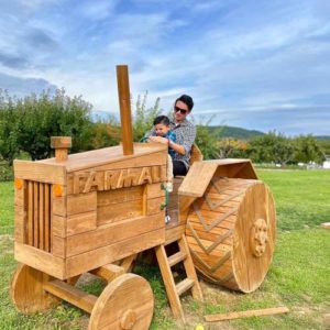 A father and child sit on a wooden tractor