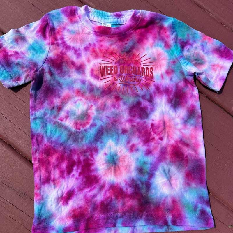 a tie dye shirt with the Weed orchards logo on the front