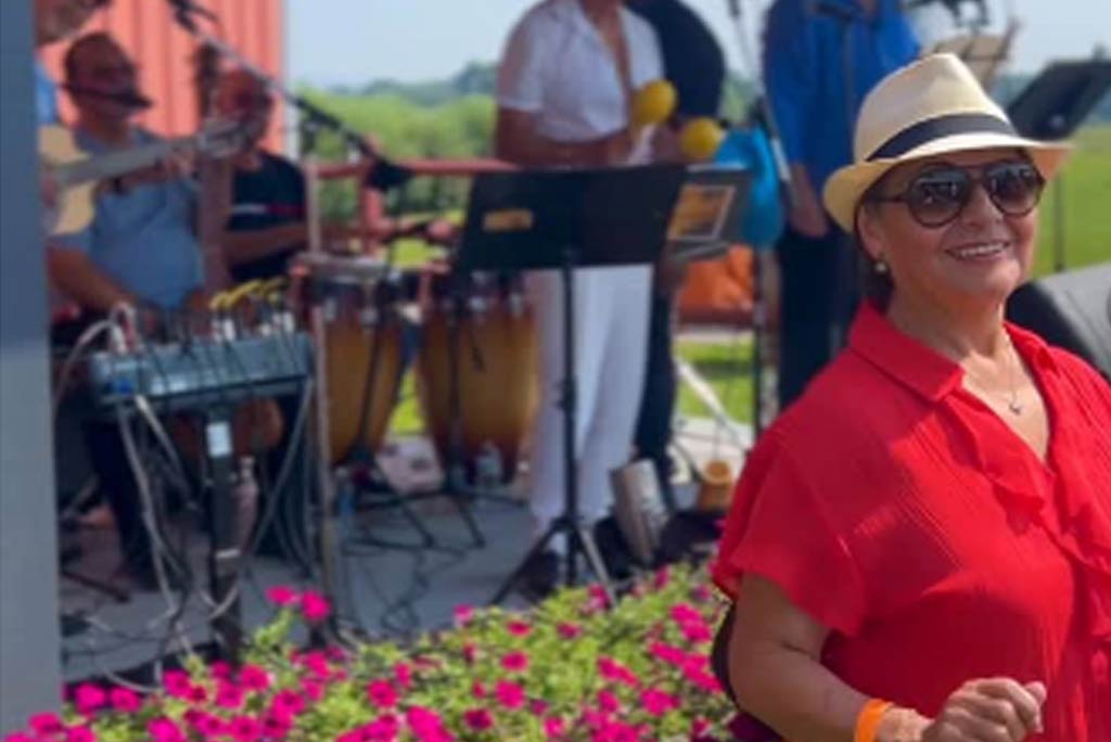 A woman dances in front of a mariachi band on an outside stage.
