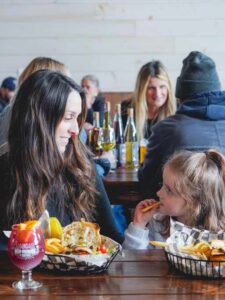 A woman and daughter share lunch at a table inside winery and cafe.