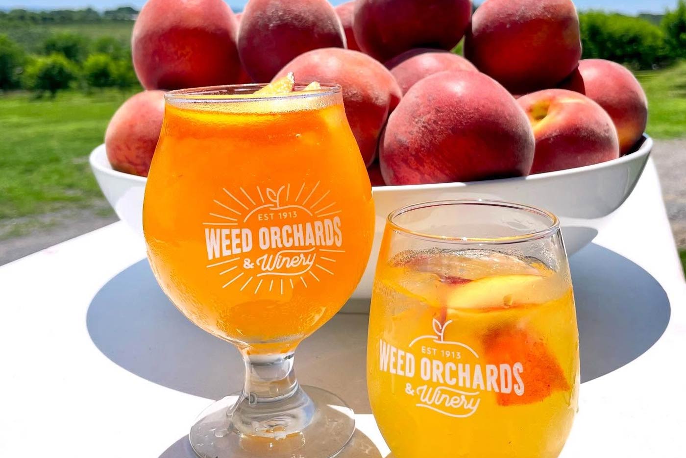 A close up of an orange colored sangria with slice peaches in it.